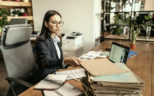 A business owner working through paperwork at a desk with a laptop (stock photo)