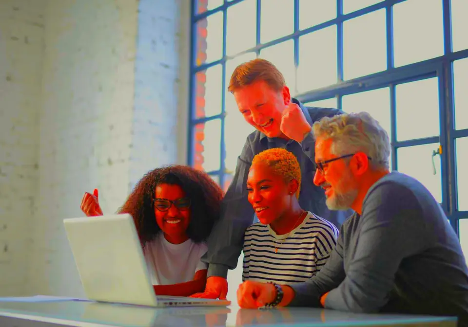 Two people working together at a laptop in a bright office (stock photo)