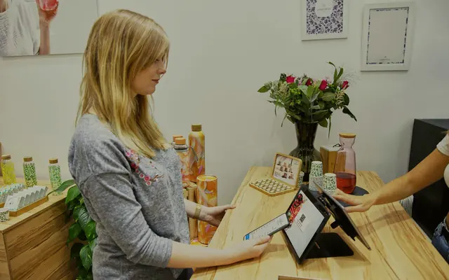 A shopper paying by tablet at a small shop counter (stock photo)